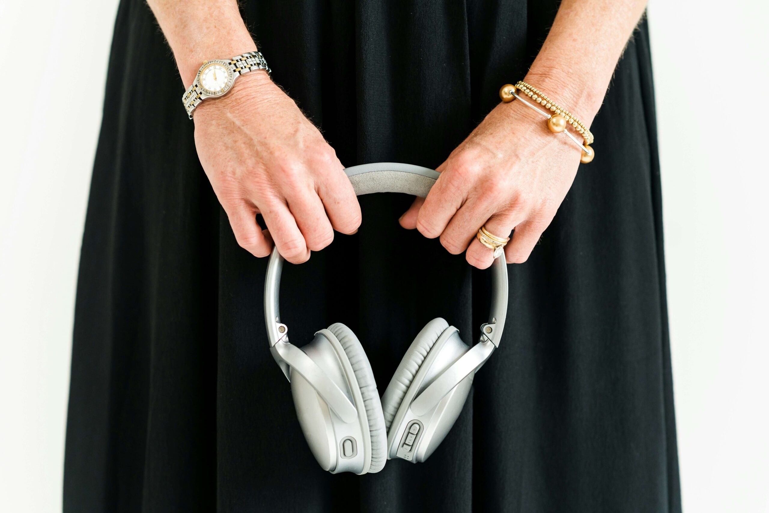 Woman holding silver headphones, ready to listen to a wedding podcast for business inspiration – Boda Bliss