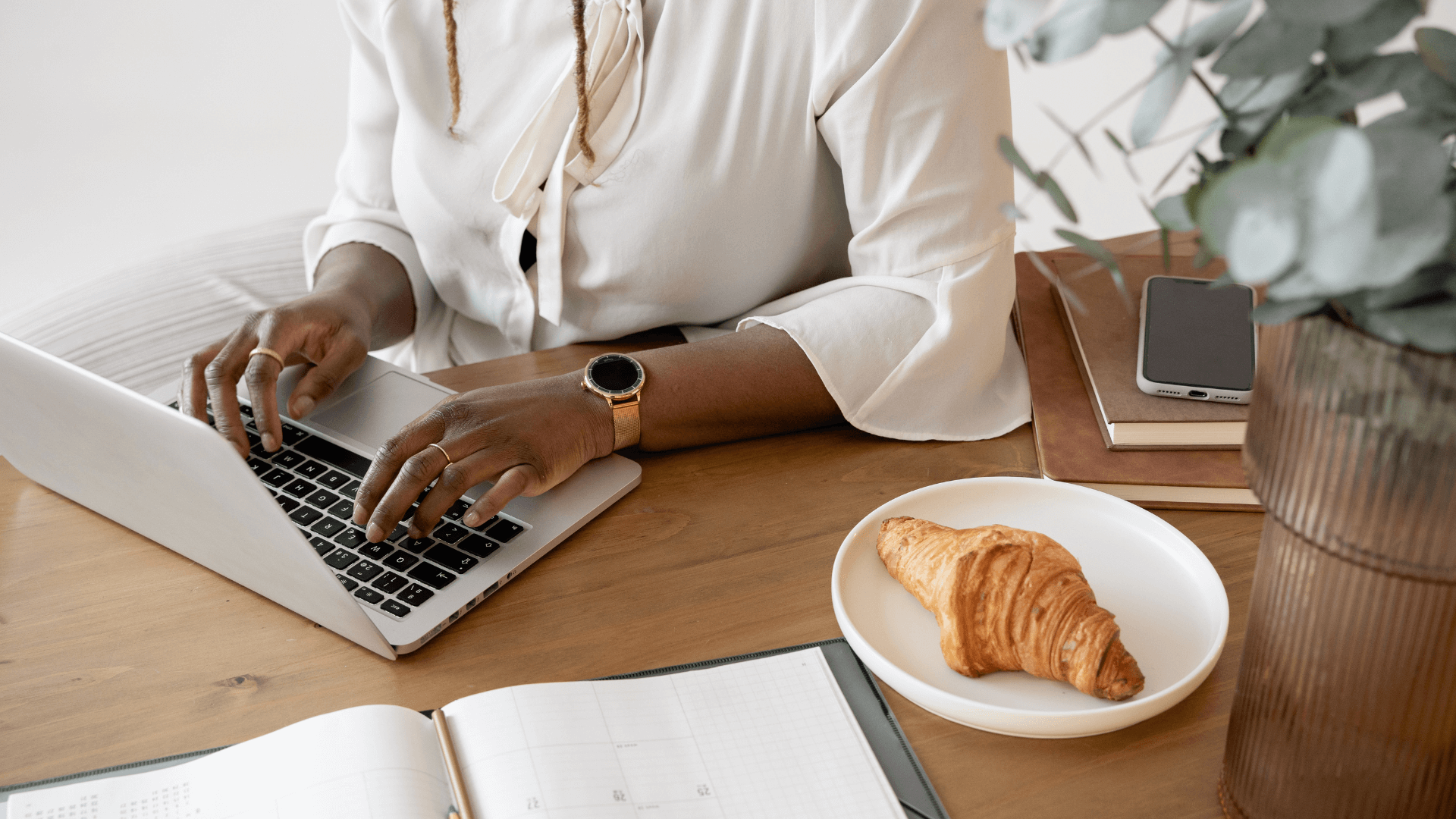 Wedding professional working on laptop with planner and coffee representing modern project management for creative entrepreneurs