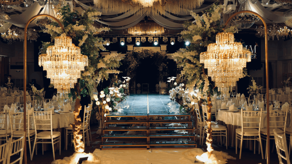 Luxury ballroom wedding venue with crystal chandeliers, lush greenery installations, and elegant table settings for formal reception
