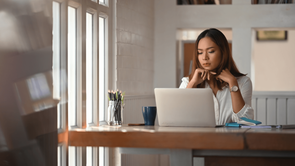 A wedding professional deep in thought at a laptop, planning goals for business growth.