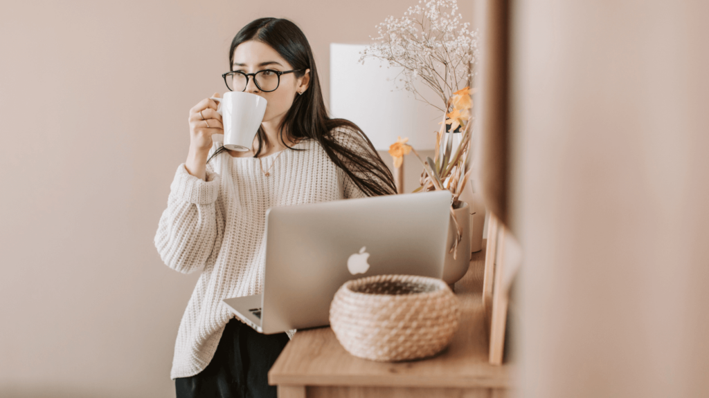 Woman sipping coffee while working on a laptop. 