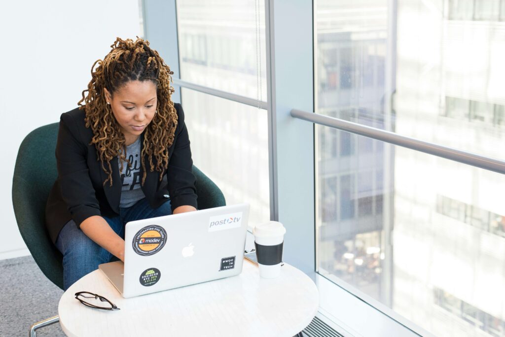 Woman working on a laptop at a modern office with a coffee cup beside her.