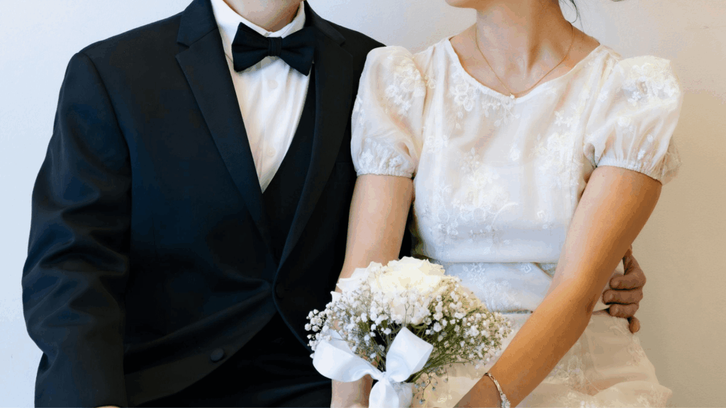 Wedding couple standing together in classic attire, with the bride holding a bouquet, representing modern wedding professionals and services.