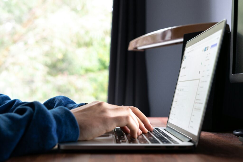 writing a blog on wordpress on a laptop desk with green trees outside the window