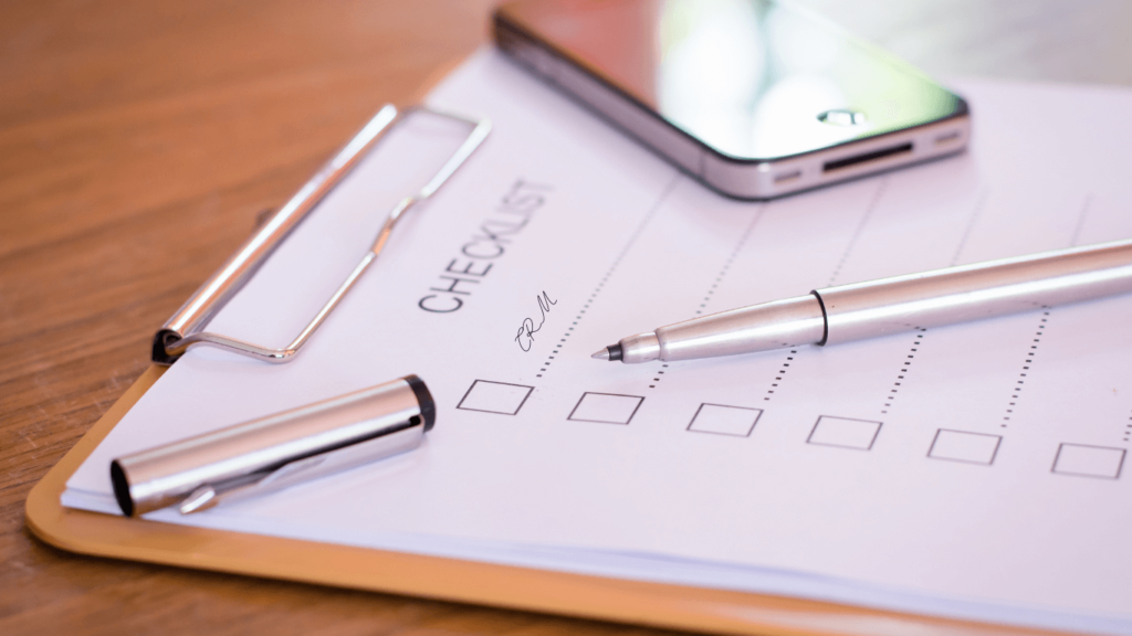 Checklist and pen on a clipboard with a smartphone nearby, symbolizing organization and task management for CRMs