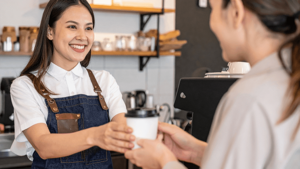 Barista handing a coffee to a customer, representing customer experience and marketing goals for a creative small business.