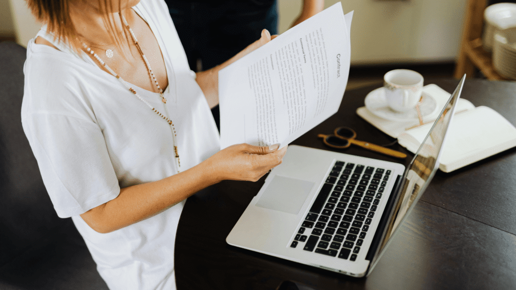 Wedding planner reviewing digital contract and proposal using CRM software at laptop with coffee