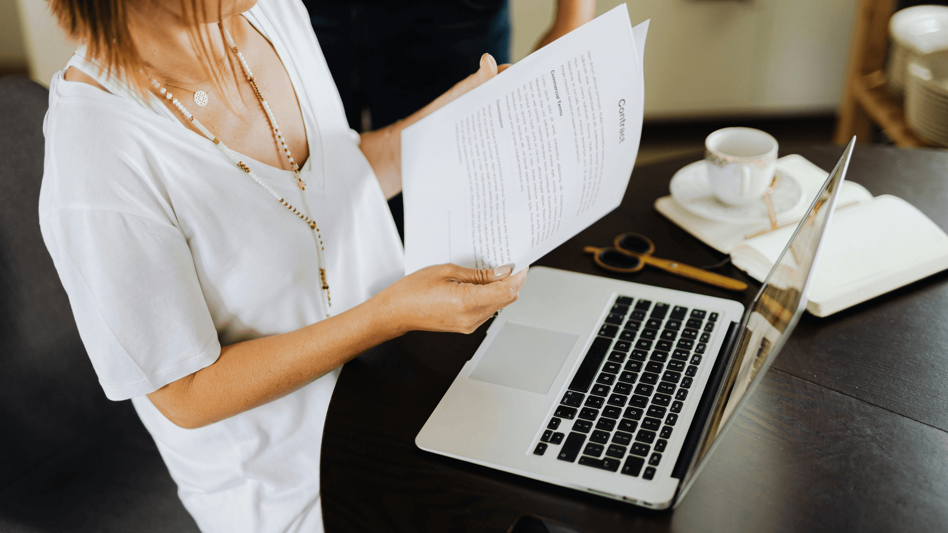 Wedding planner reviewing digital contract and proposal using CRM software at laptop with coffee