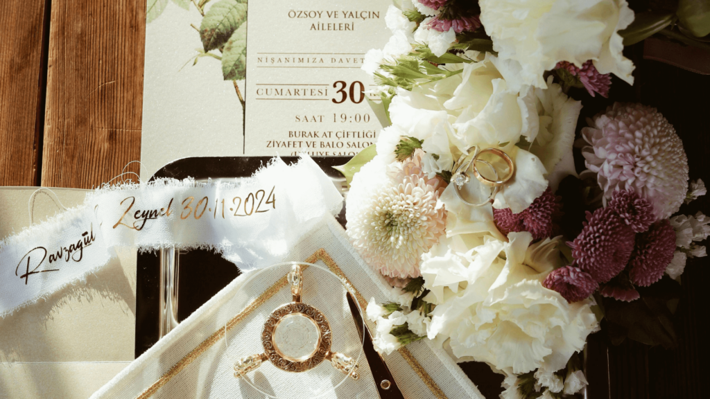 A beautifully styled flat lay of a wedding invitation suite with fresh flowers, gold accents, and elegant calligraphy.