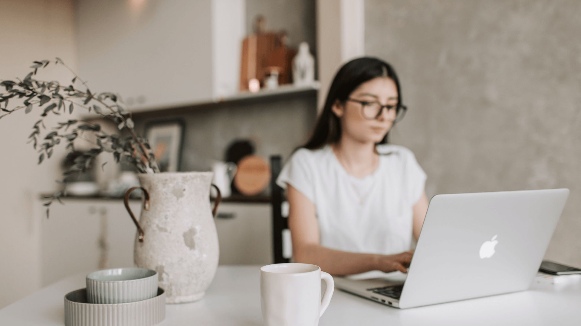 Female wedding business owner researching vendor directories on a laptop at home, evaluating Zola and The Knot listings.