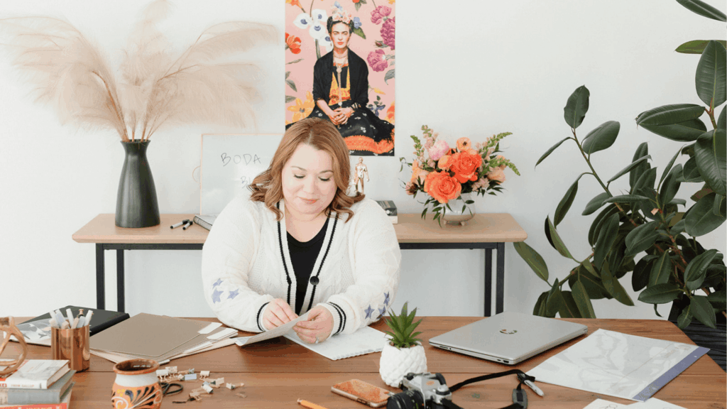 Cinthia Onines, systems and marketing strategist, working at her desk surrounded by flowers, laptop, and creative tools, showcasing workflow optimization.