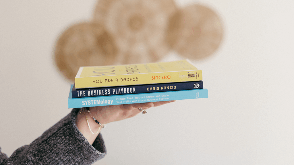Stack of business books including The Business Playbook and SYSTEMology, symbolizing systems strategy and workflow automation for growth.