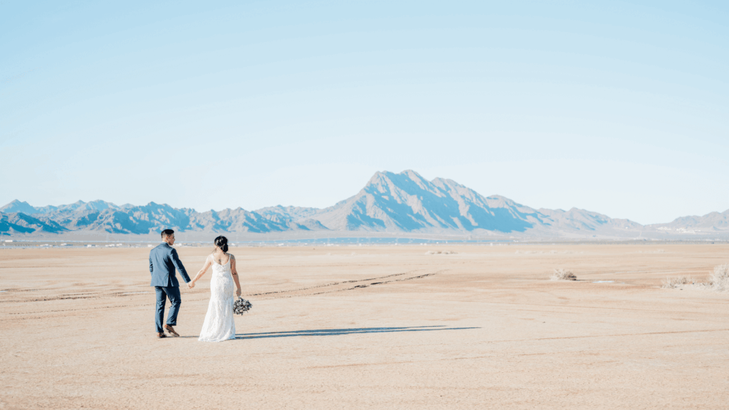 Gen Z wedding couple walking outdoors in desert landscape with mountains