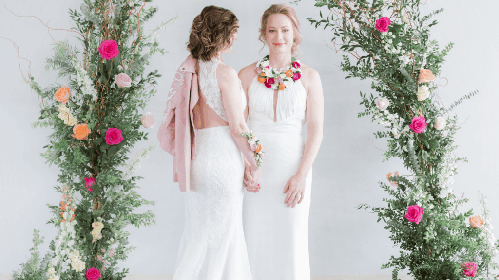 Inclusive Gen Z wedding couple standing under a floral arch