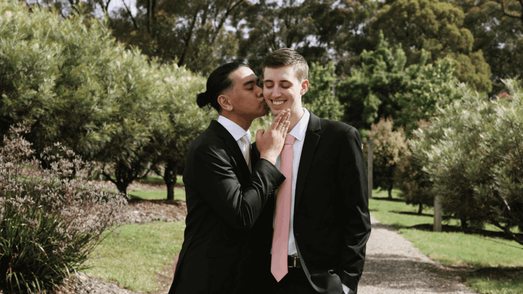 Two grooms sharing a joyful moment outdoors, symbolizing same-sex inclusion and representation in wedding PR and marketing.