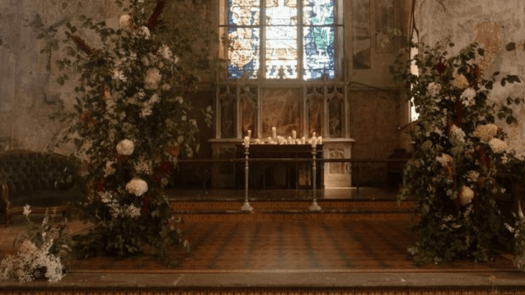 Literary romance wedding ceremony in an intimate chapel with layered florals and candlelight, inspired by storytelling-driven 2026 wedding trends.