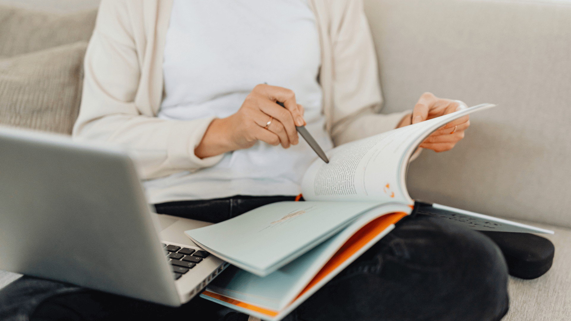 Woman reviewing a book and laptop during a monthly KPI review for marketing clarity