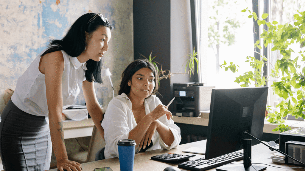 Two small business owners reviewing their marketing systems and workflows together at a computer.