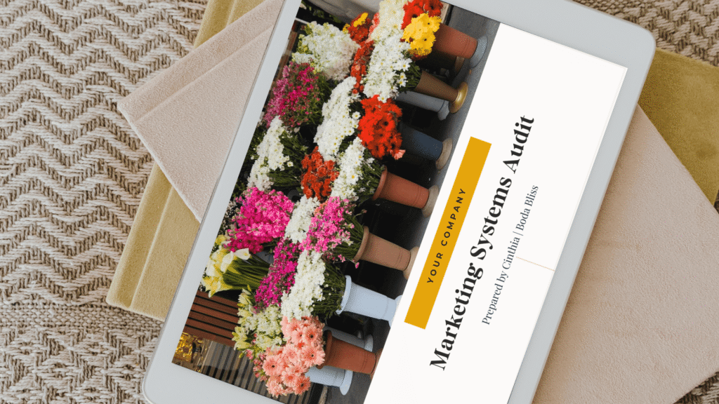A tablet displaying a Boda Bliss Marketing Systems Audit report for a wedding florist or creative business, sitting on a textured flat-lay surface.
