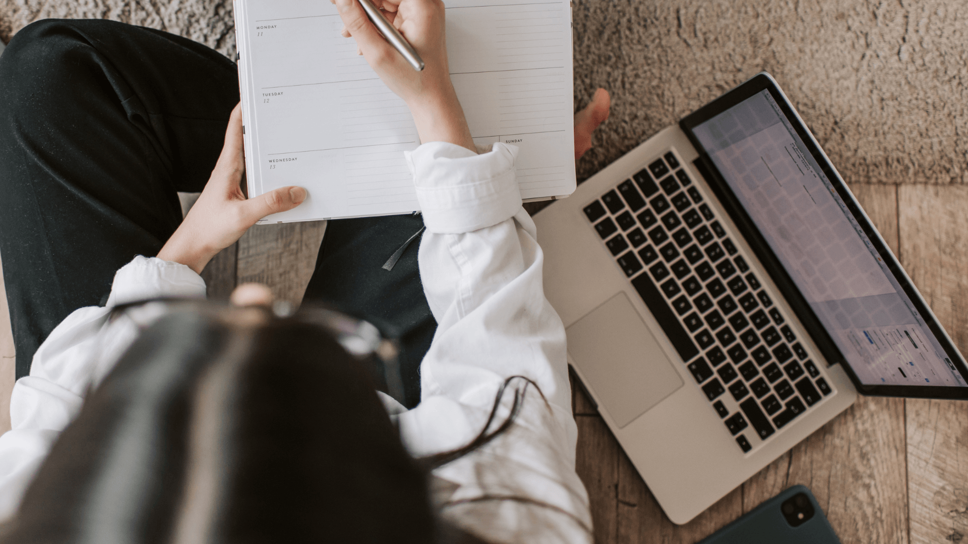 Small business owner planning her marketing system using a weekly planner and laptop.