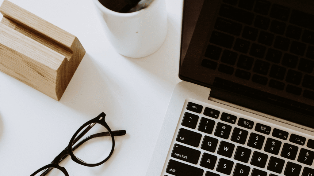 Organized workspace with a laptop, coffee, and glasses representing a structured small business marketing system.