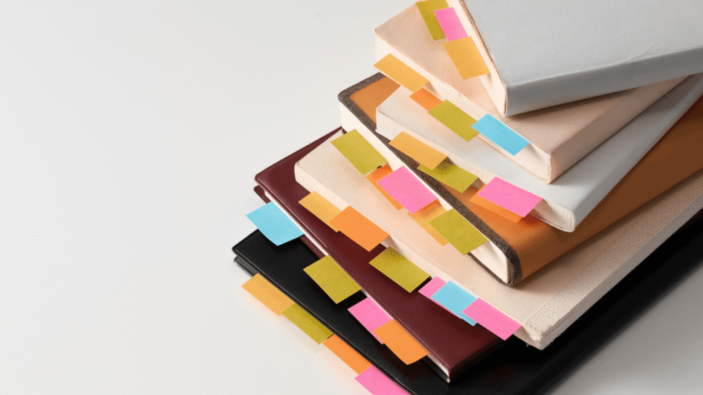 Stack of books with colorful tabs representing research, planning, and content organization for marketing visibility.