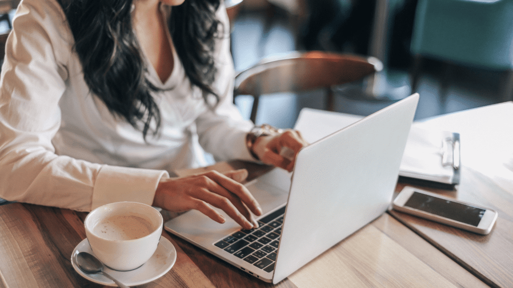 Small business owner working on her marketing strategy and AI search visibility on a laptop at a cafe