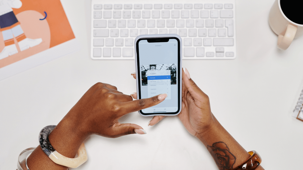 Business owner reviewing marketing content on a smartphone beside a keyboard and coffee mug
