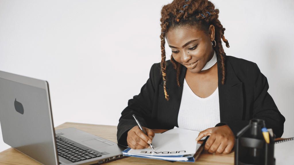 Business owner planning her marketing strategy with a laptop and notebook at her desk.
